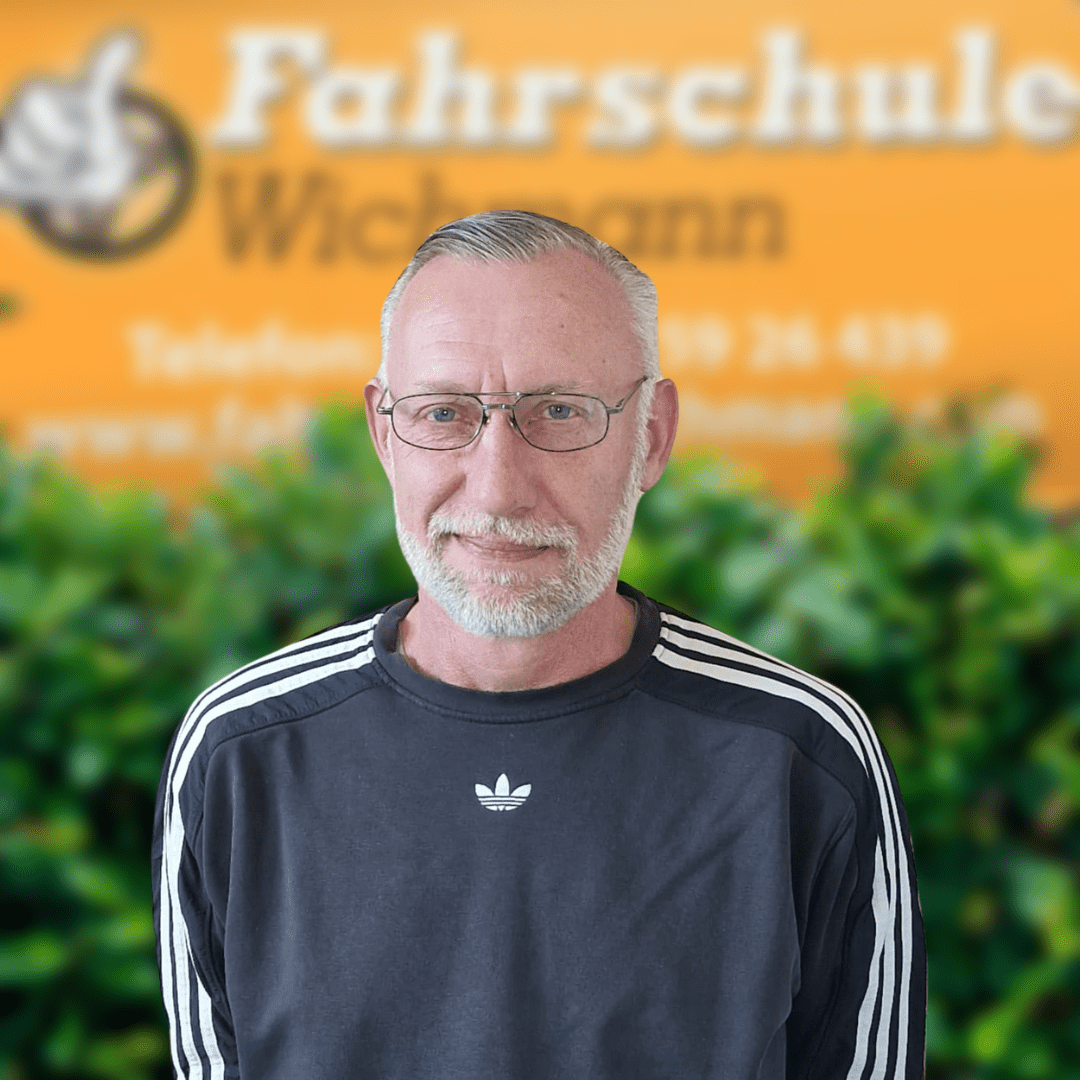 Peter, Fahrlehrer der Fahrschule Wichmann in Delmenhorst, steht vor dem Logo der Schule. Spezialisiert auf Autoführerschein, Motorradführerschein, LKW- und Anhängerführerschein, Intensivfahrschule sowie Fahrlehrerausbildung. - Fahrschule Wichmann Delmenhorst - Autoführerschein LKW Führerschein Motorradführerschein Peter, Fahrlehrer der Fahrschule Wichmann in Delmenhorst, vor Logo mit Fokus auf Führerscheine und Fahrlehrerausbildung.