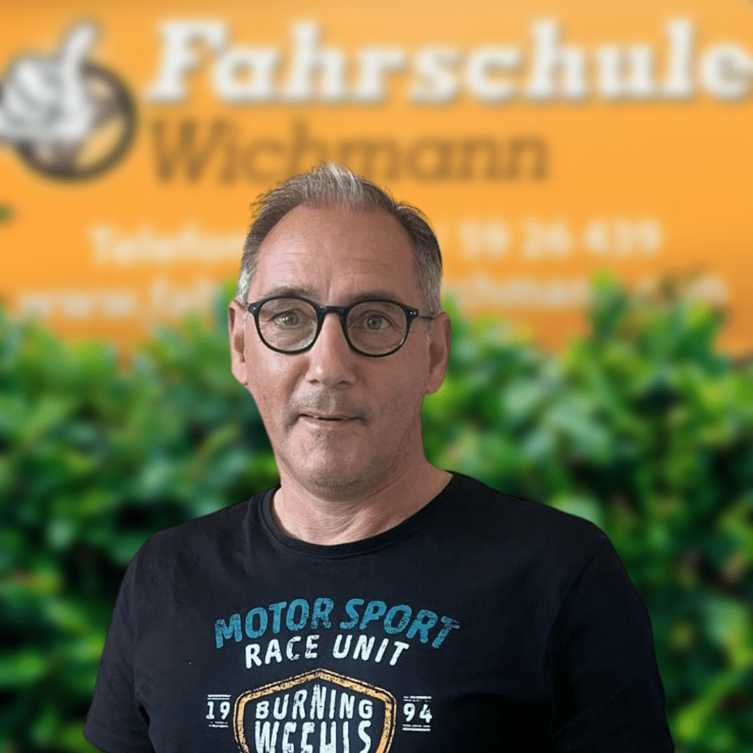 Thomas, Fahrlehrer der Fahrschule Wichmann in Delmenhorst, steht für moderne Ausbildung in Autoführerschein, Motorradführerschein, LKW Führerschein, Anhängerführerschein, Intensivfahrschule und Fahrlehrerausbildung. - Fahrschule Wichmann Delmenhorst - Autoführerschein LKW Führerschein Motorradführerschein Thomas, Fahrlehrer der Fahrschule Wichmann in Delmenhorst, vor dem gelben Firmenschild mit Logo.