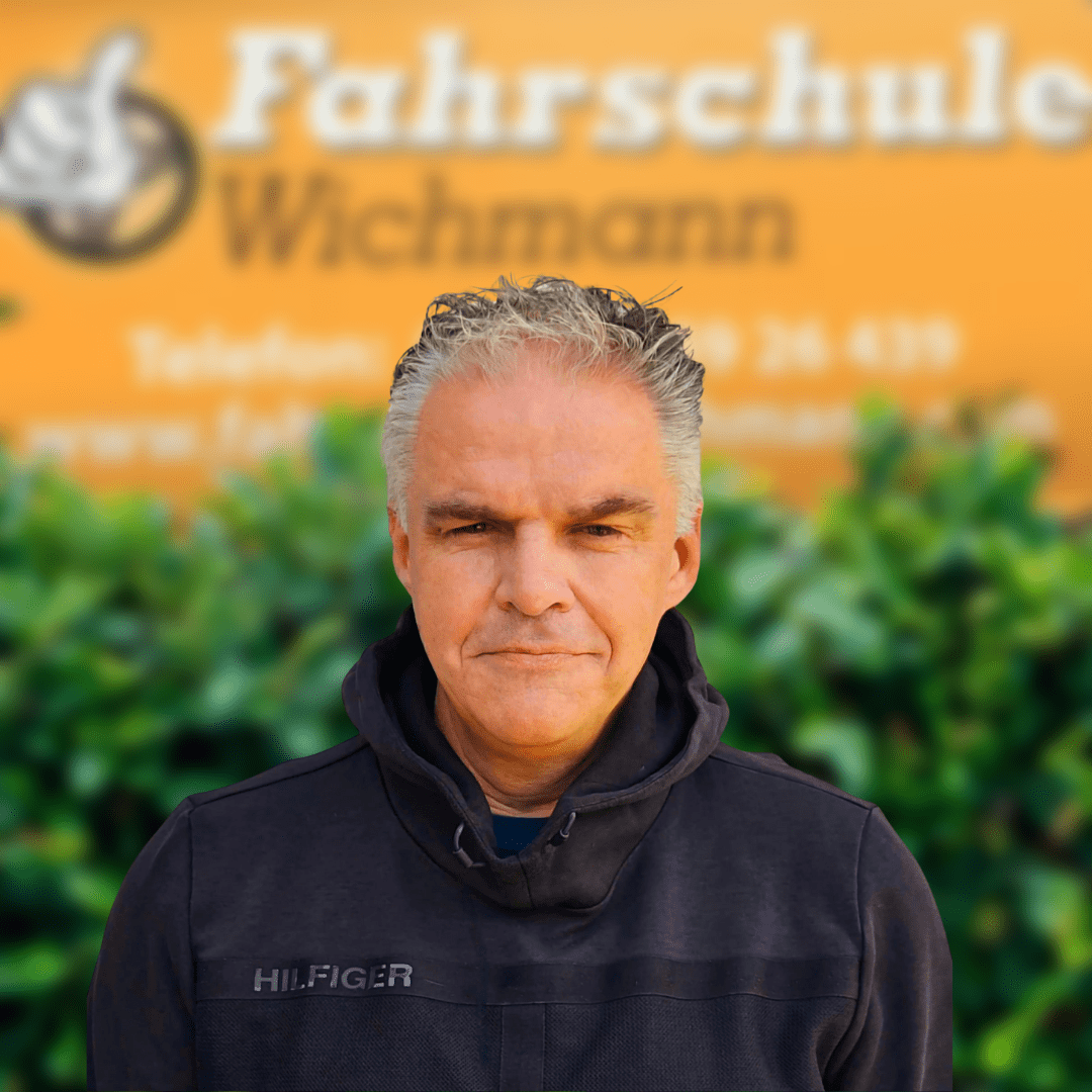 Thomas, erfahrener Fahrlehrer der Fahrschule Wichmann in Delmenhorst, bereitet Fahrschüler professionell auf den Autoführerschein, Motorradführerschein, Anhängerführerschein, LKW Führerschein und die Fahrlehrerausbildung in der Intensivfahrschule vor. - Fahrschule Wichmann Delmenhorst - Autoführerschein LKW Führerschein Motorradführerschein Thomas, Fahrlehrer der Fahrschule Wichmann in Delmenhorst, vor dem gelben Firmenschild.